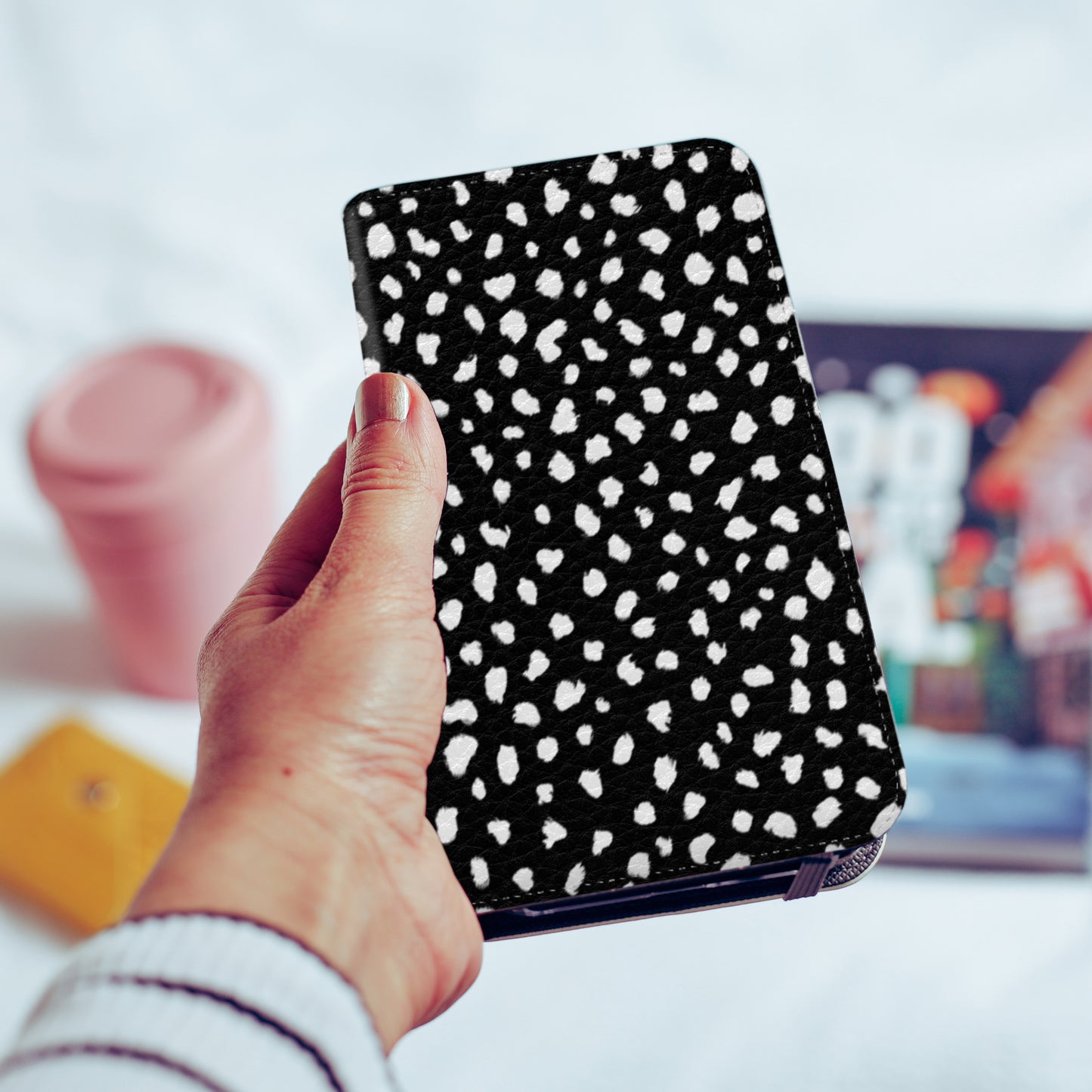 A hand holding out a polka dot memphis black and white wallet phone case | harper & blake