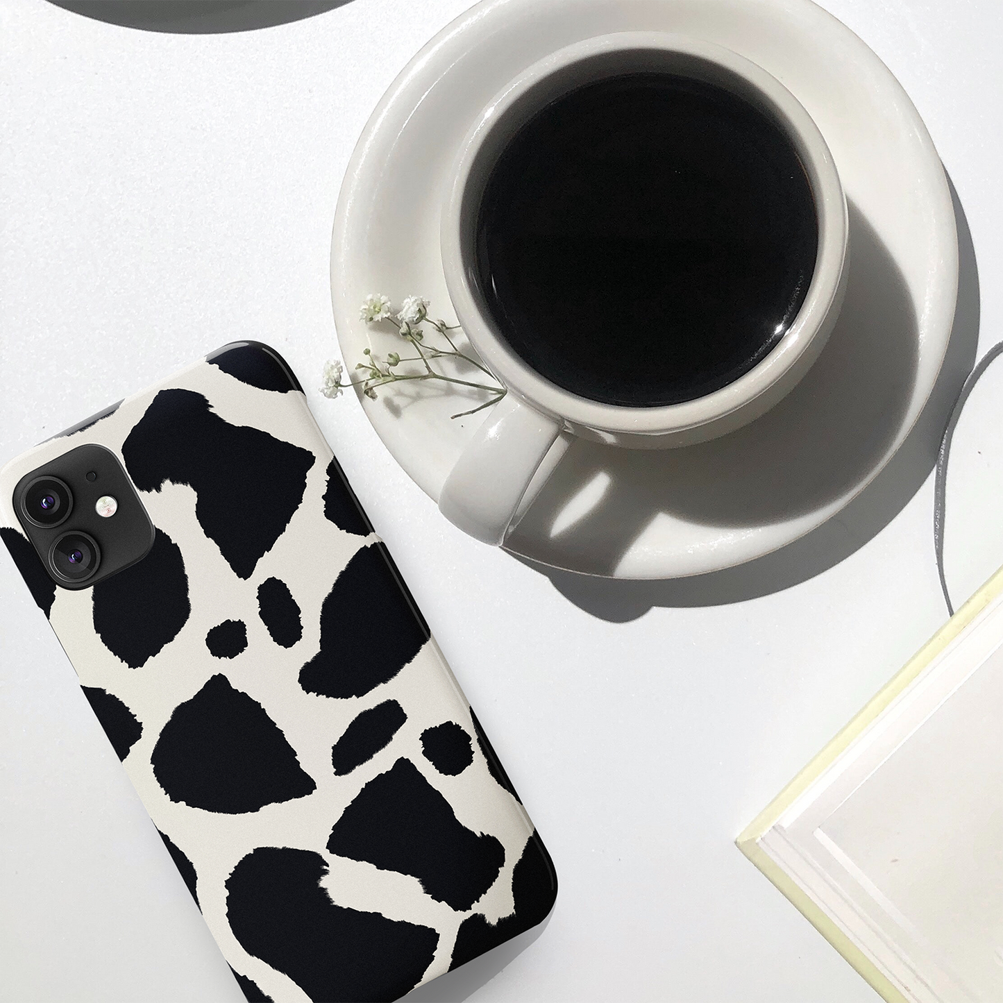cow animal print phone case lying on a white table next to a cup of black coffee | Harper & Blake