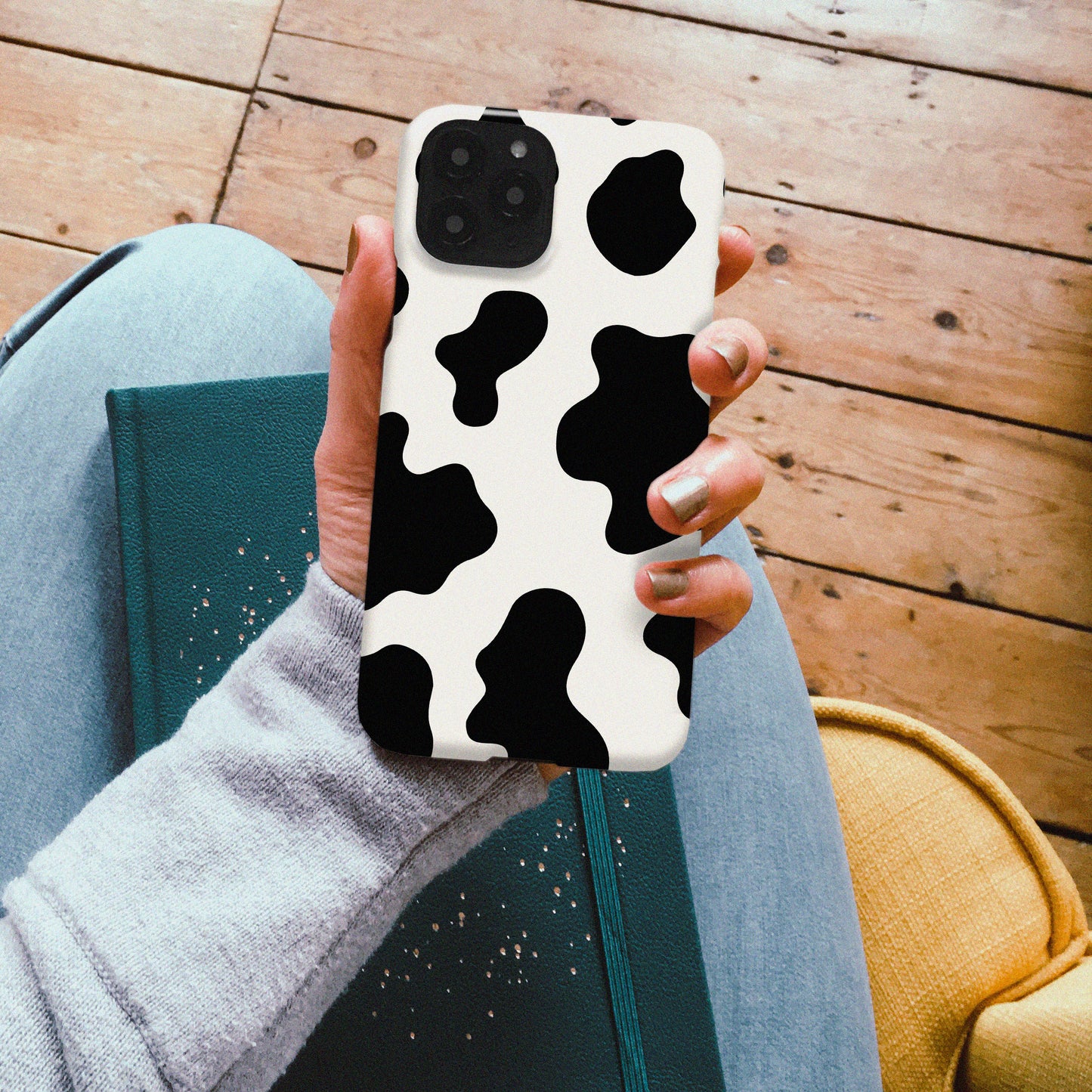 A hand holding a cow print phone case from harper & blake