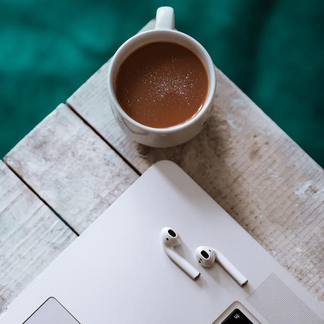 AirPods on a Macbook on a wooden table