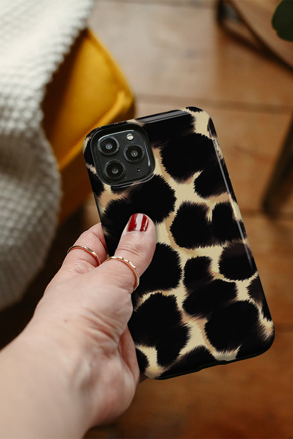 Hand holding a phone with an abstract animal print on it 