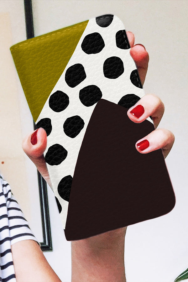 Phone case with black and white polka dot design held by a person.