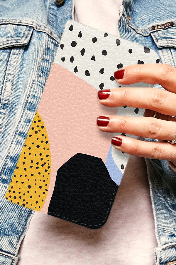 Hand holding a wallet phone case with an abstract polka dot designs with block colours