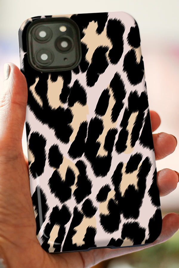 Phone case with leopard print held by a hand against a blurred background