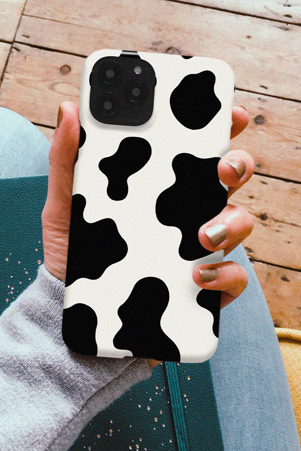Hand holding a phone with a cow print design on it 