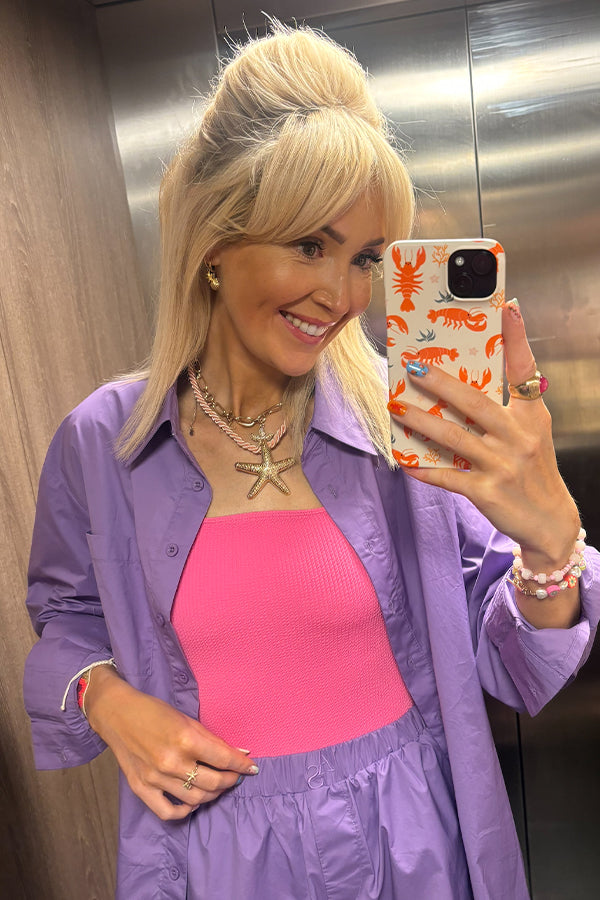 Woman taking a mirror selfie holding a phone case with a lobster pattern on it 