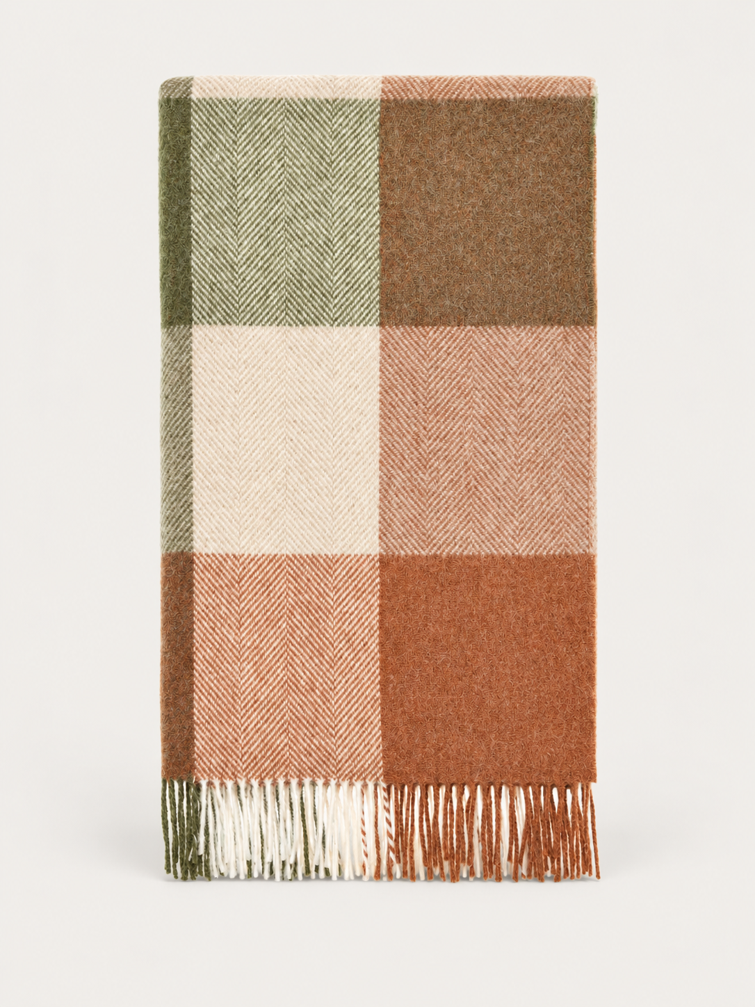 A folded plaid wool blanket with a herringbone pattern in muted shades of green, brown, cream, and terracotta, finished with fringed edges, shown on a light gray background.