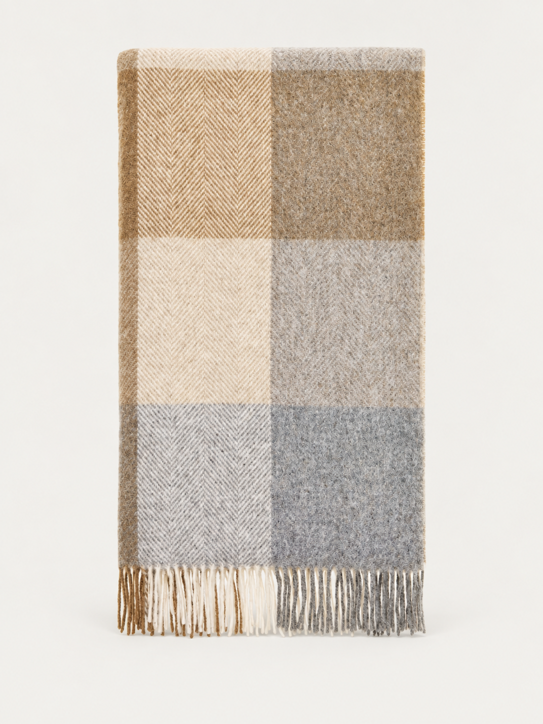 A folded plaid throw blanket with fringed edges, featuring a checkered pattern in beige, brown, cream, gray, and light blue-gray on a plain white background.