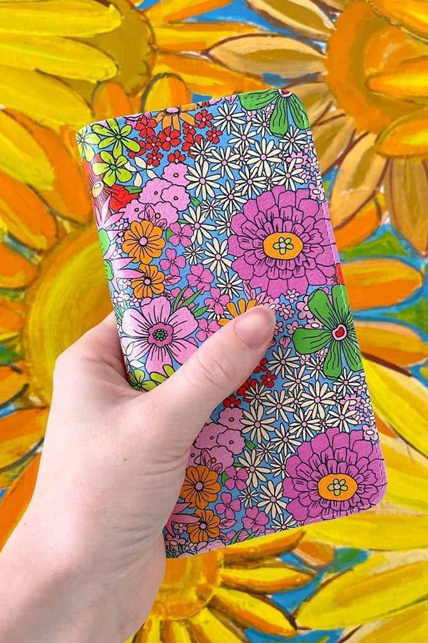 Colorful floral phone case held by a hand with sunflower background
