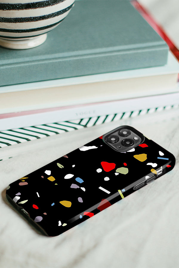 Phone case with a black background with a colourful terrazzo pattern 