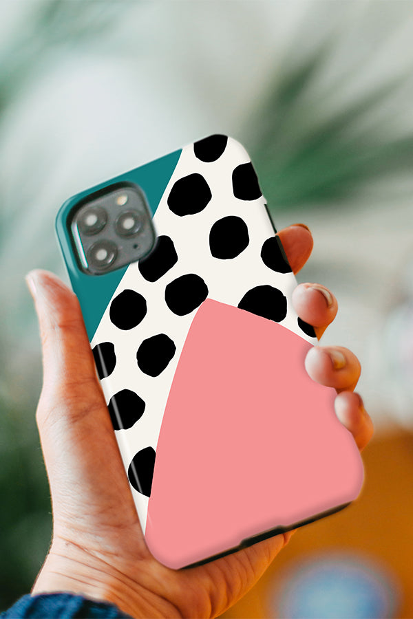 Hand holding a phone with an abstract design with large polka dots and abstract shapes