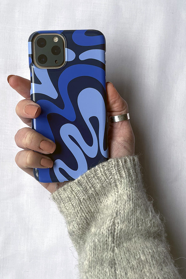 Hand holding a phone with a blue and white abstract patterned case against a white background