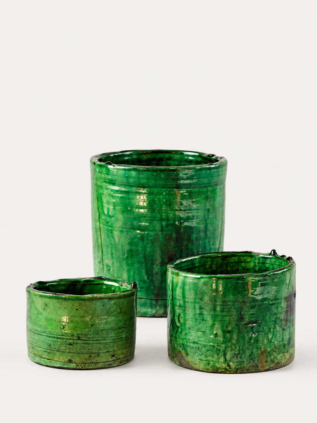Three green glazed ceramic planters in different heights, arranged on a light gray background.
