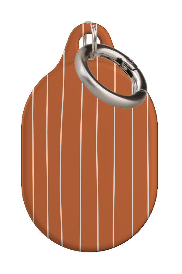 fine line AirTag case back view with a burnt orange base and thin hand drawn white stripes